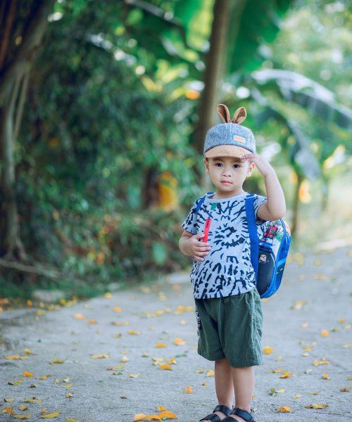 Adorable young boy with backpack enjoying a summer day outdoors, exuding joy and innocence.